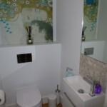 white bathroom with abstract picture above toilet