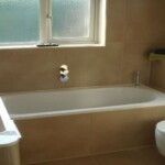 long bath with brown sink and toilet