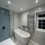white bath with silver taps and towel rail