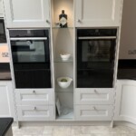 white cupboards with cooker built into shelving unit