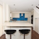 white and blue kitchen next to stairs