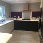 white and black kitchen with purple walls next to hob