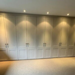 Fitted bedroom wardrobes with modern panelled doors and spotlights